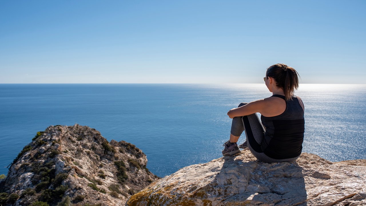Mujer contemplando la playa desde el mirador